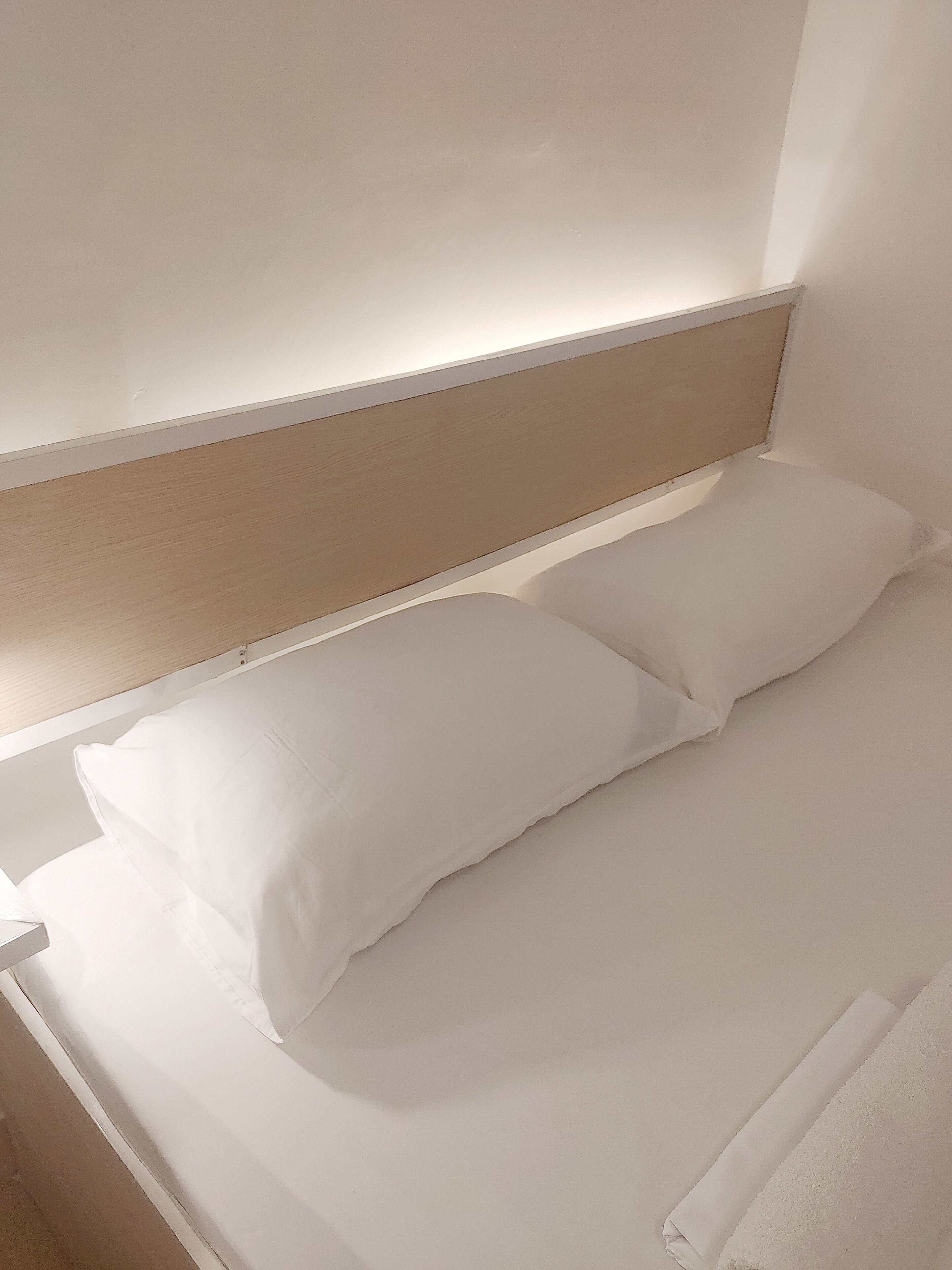 Una cama con ropa blanca y cabecera de madera en una habitación de hotel.