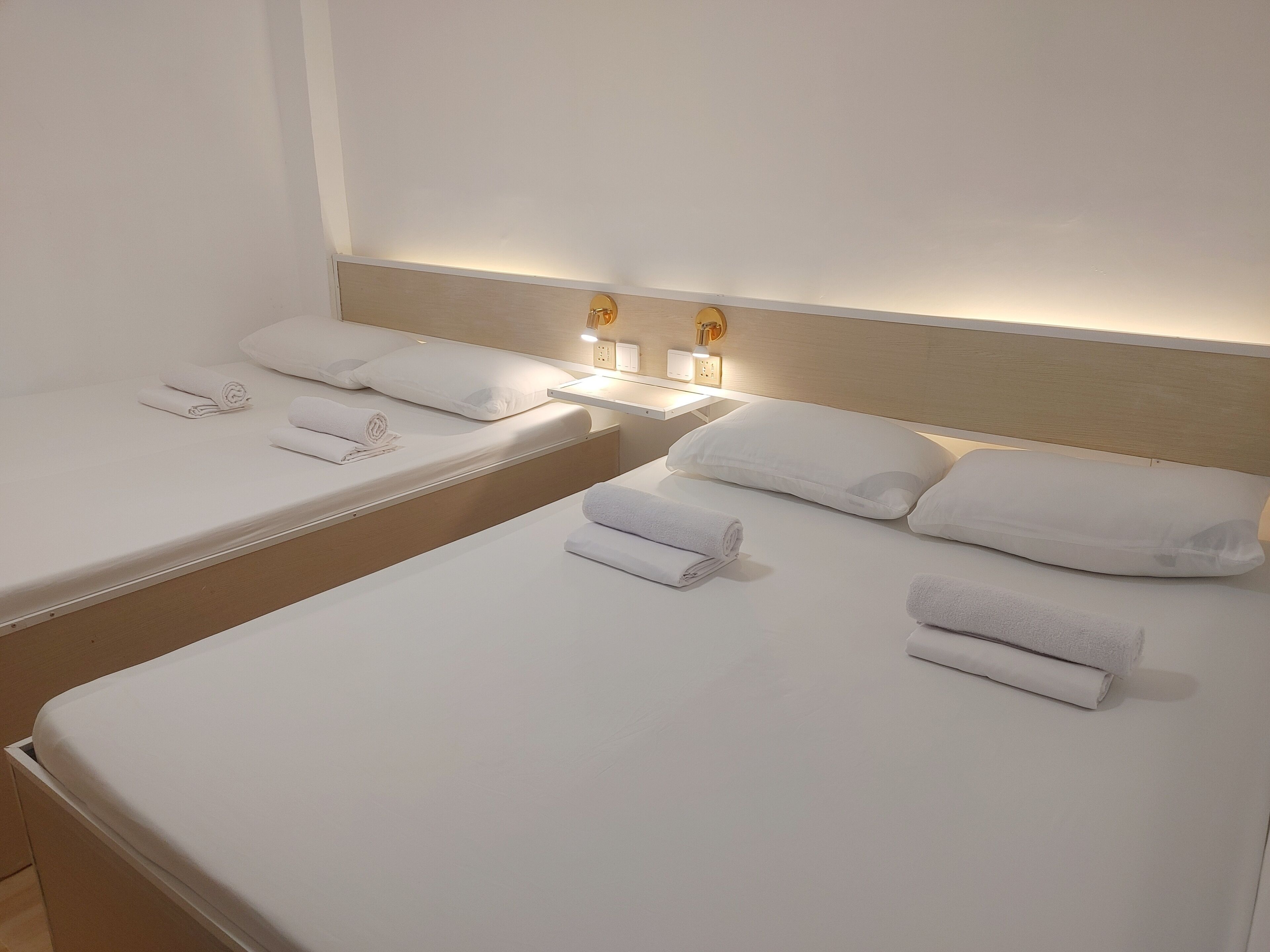 A hotel room with two single beds, each with a neatly folded towel and a pillow.