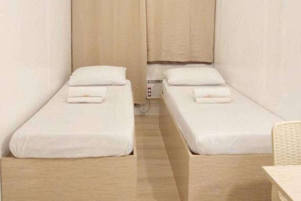 Ein kleines Einzelzimmer mit zwei Einzelbetten, Holzboden und schlichtem, zweckmäßigem Design.
