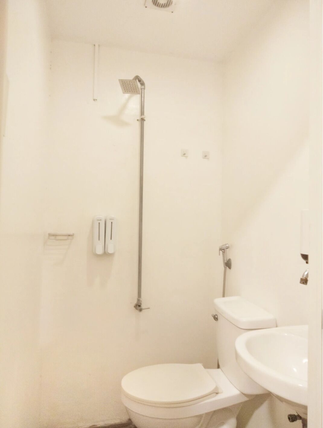 Ein kleines, weißes Badezimmer mit Toilette, Waschbecken und Dusche.