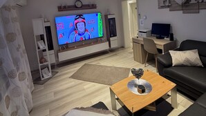 A modern living room with a flat-screen TV, a wooden coffee table, a sofa, and a desk with a computer. - Cozy 2 X room, kitchen bathroom apartment in the Karl Marx Siedlung in Worms 1st floor (Worms)