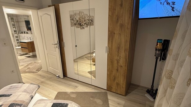 A bedroom with a bed, a wardrobe, a television, and a mirror. - Cozy 2 X room, kitchen bathroom apartment in the Karl Marx Siedlung in Worms 1st floor (Worms)