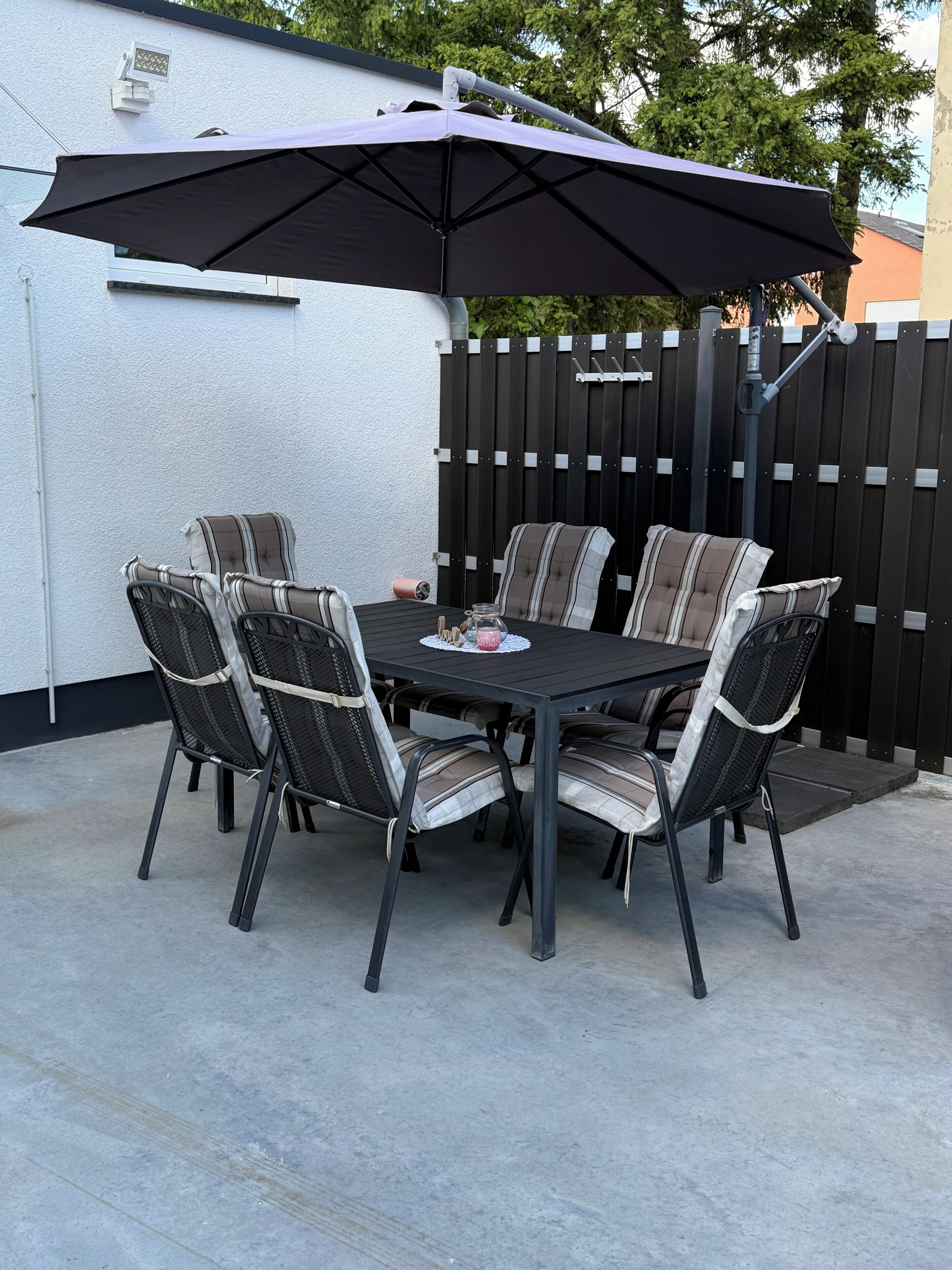 A patio with a table and chairs, an umbrella, and a fence.