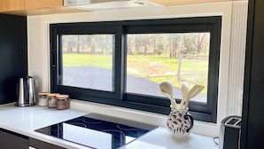 Eine moderne Küche mit Einbauherd, Backofen und einem Fenster mit Blick auf eine Rasenfläche.