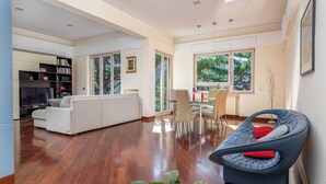 A spacious living area with a sofa, a dining table with chairs, a TV, and a bookshelf. - Pine House (Sorrento)