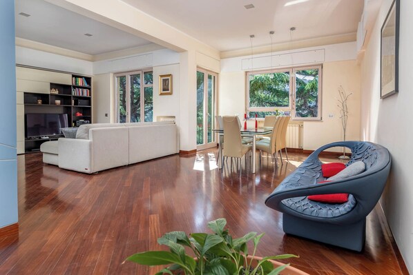 A spacious living area with a sofa, a dining table with chairs, a TV, and a bookshelf. - Pine House (Sorrento)