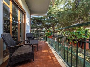 A balcony with wicker chairs, a potted plant, and a railing. - Pine House (Sorrento)