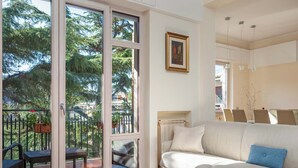 A living room with a white sofa, a glass door leading to an outdoor area with a patio and chairs, and a painting on the wall. - Pine House (Sorrento)