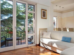 A living room with a white sofa, a glass door leading to an outdoor area with a patio and chairs, and a painting on the wall. - Pine House (Sorrento)