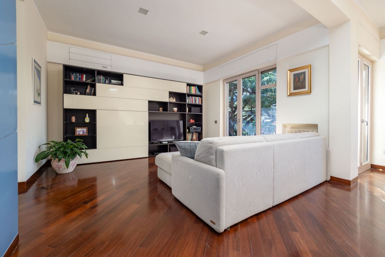 A modern living room with a sofa, a television, and built-in bookshelves.