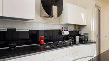 A modern kitchen with white cabinets, a black countertop, and a built-in oven.