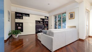 Een moderne woonkamer met een bank, een televisie en ingebouwde boekenkasten.