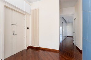 Un pasillo con suelo de madera, un radiador y una puerta con manija.
