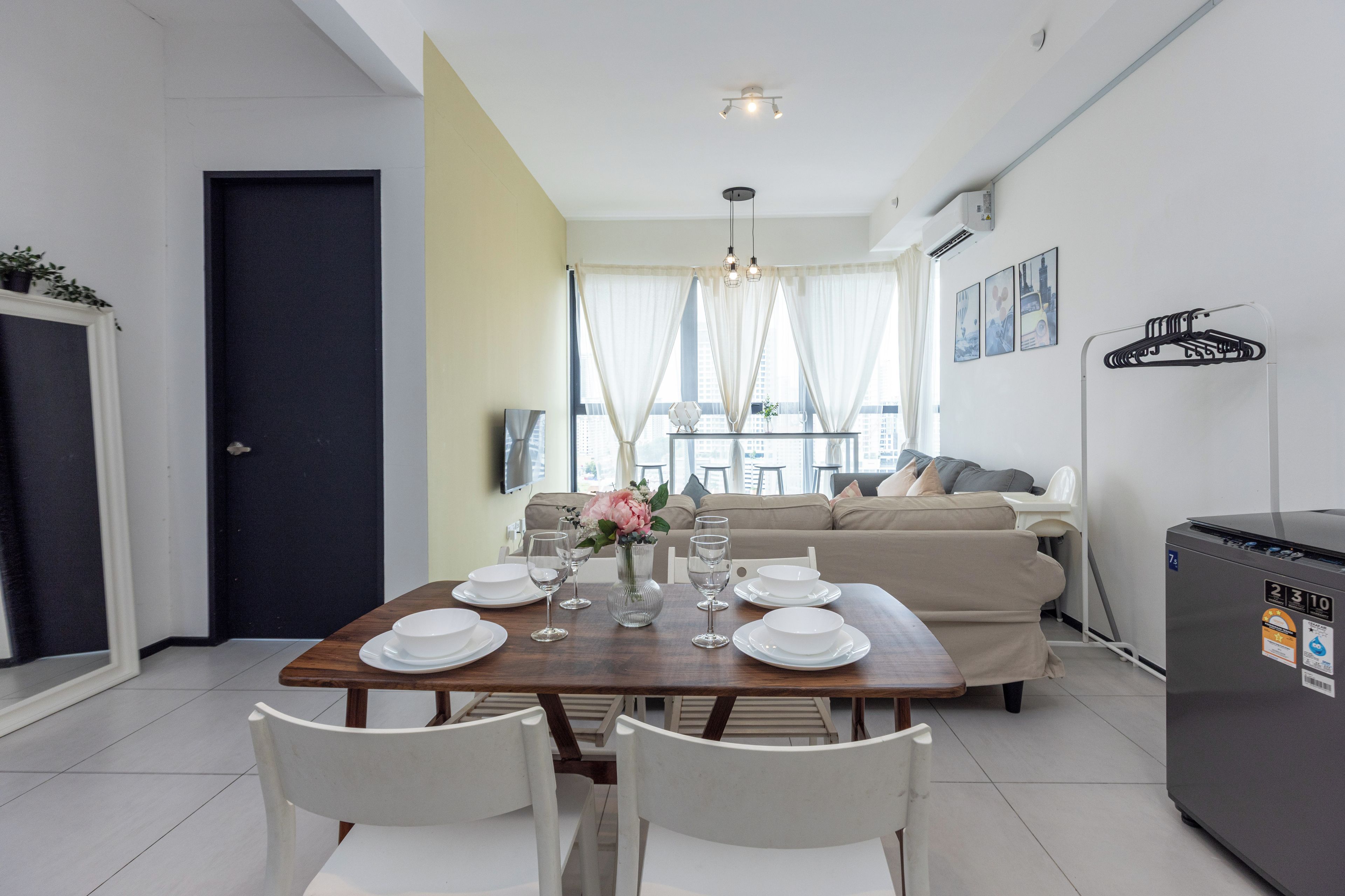 A dining area with a table set for four, a sofa, and a refrigerator.