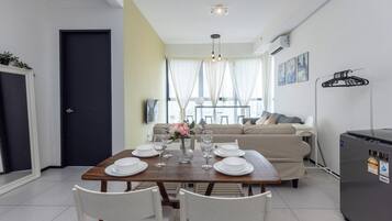 A dining area with a table set for four, a sofa, and a refrigerator.