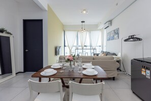 A dining area with a table set for four, a sofa, and a refrigerator. - Urban Suite Penang (George Town)