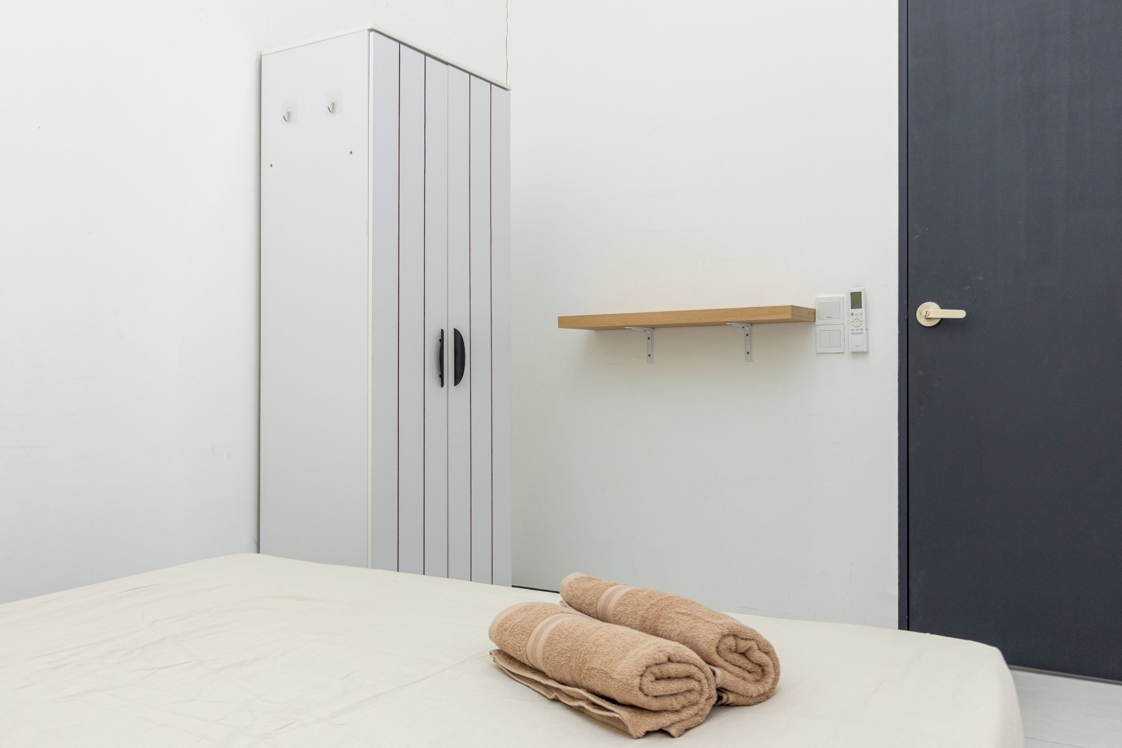 A bedroom with a bed, a wardrobe, a door, and a towel on the bed.