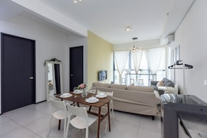 A modern living room with a dining area, a sofa set, and a TV mounted on the wall. - Urban Suite Penang (George Town)