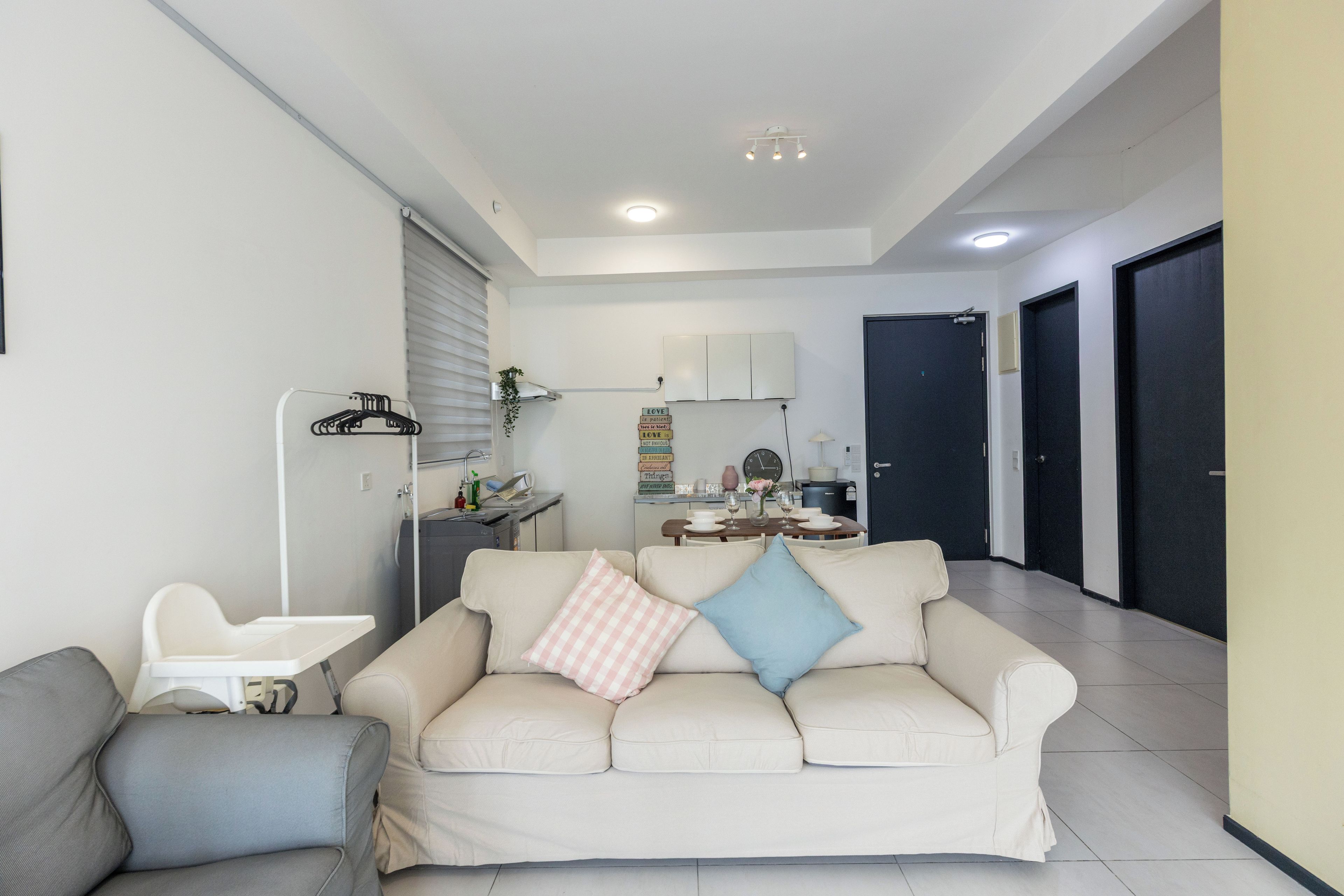 A living room with a sofa, a chair, a small table, and a kitchen area in the background.