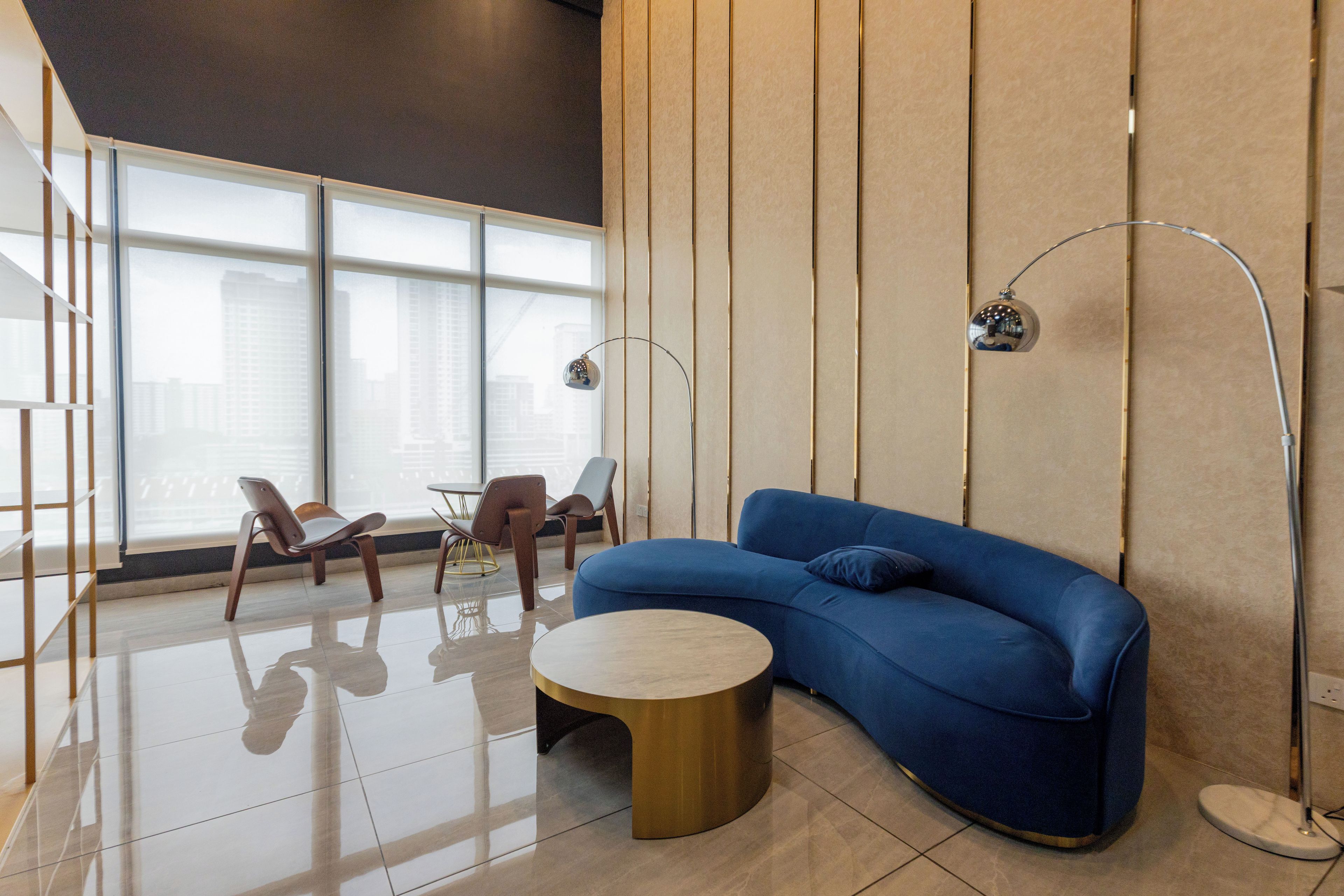 A modern living room with a blue sofa, a round coffee table, and two chairs.