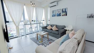 A modern living room with a grey sofa, a coffee table, and a dining area with a balcony.