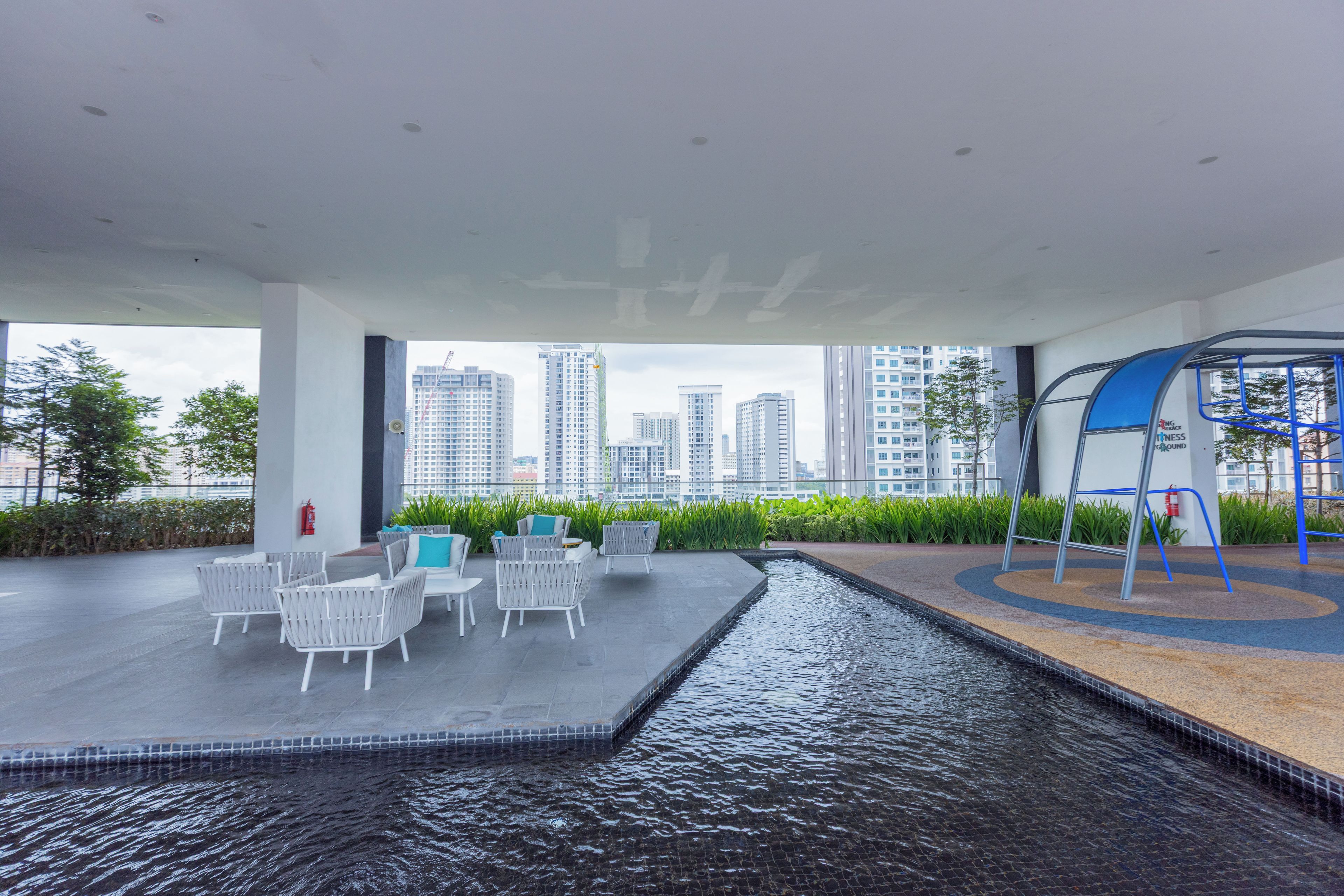 A rooftop terrace with outdoor seating, a small water feature, and a view of the city skyline.