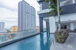 A modern building with a rooftop pool, surrounded by high-rise buildings.