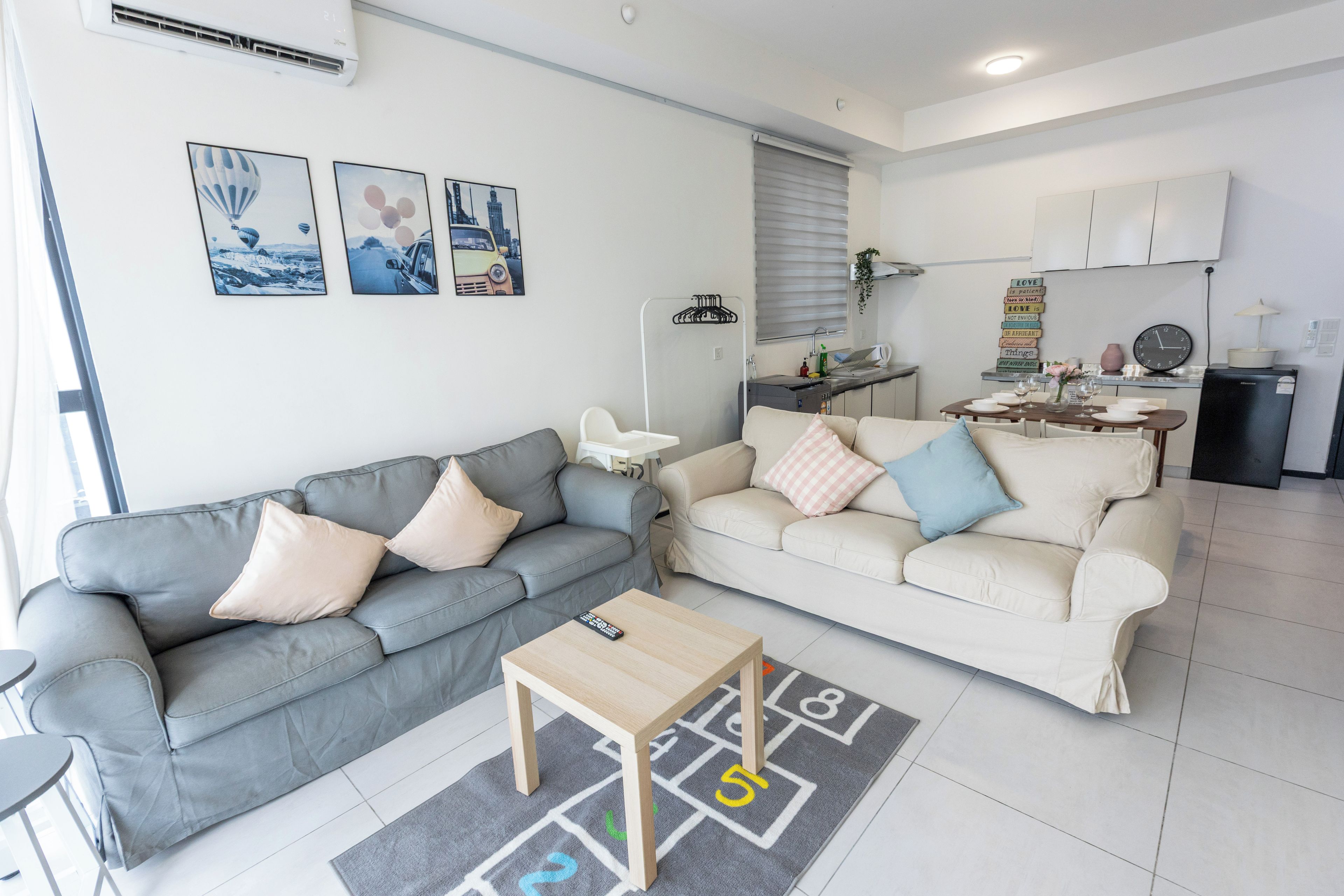 A modern living room with two sofas, a coffee table, and a kitchen area in the background.