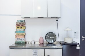 A kitchenette with a clock, a vase, and a sign with love quotes. - Urban Suite Penang (George Town)