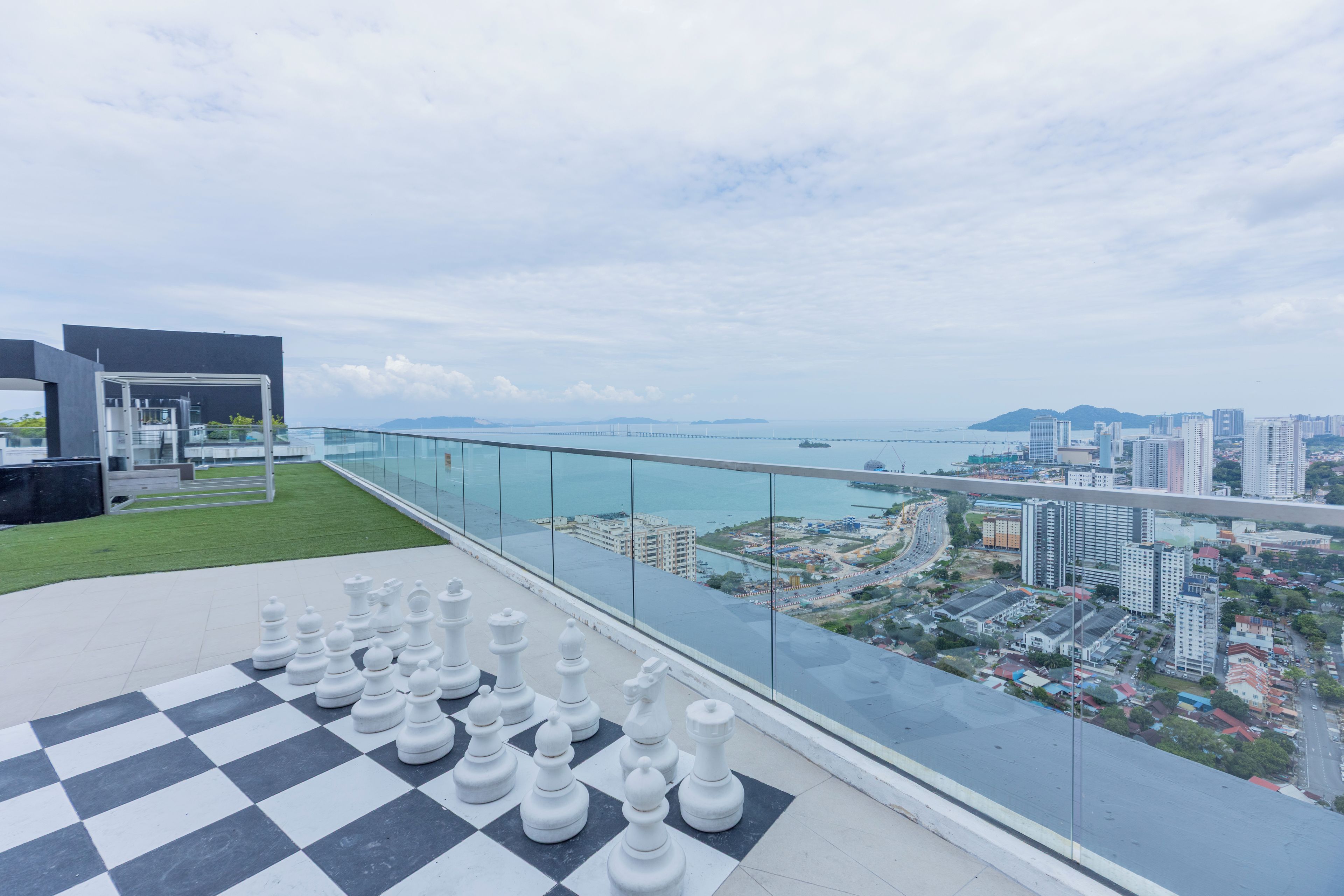 A chessboard on a balcony overlooking a cityscape with a bridge and buildings.