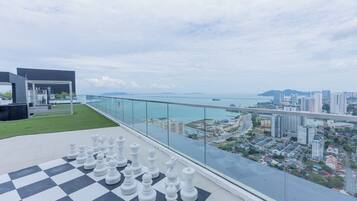 A chessboard on a balcony overlooking a cityscape with a bridge and buildings.