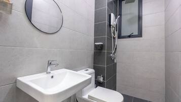Un baño moderno con lavamanos, inodoro y ducha blancos.