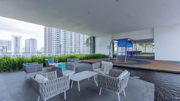 A rooftop terrace with outdoor seating, a small pool, and a playground area.