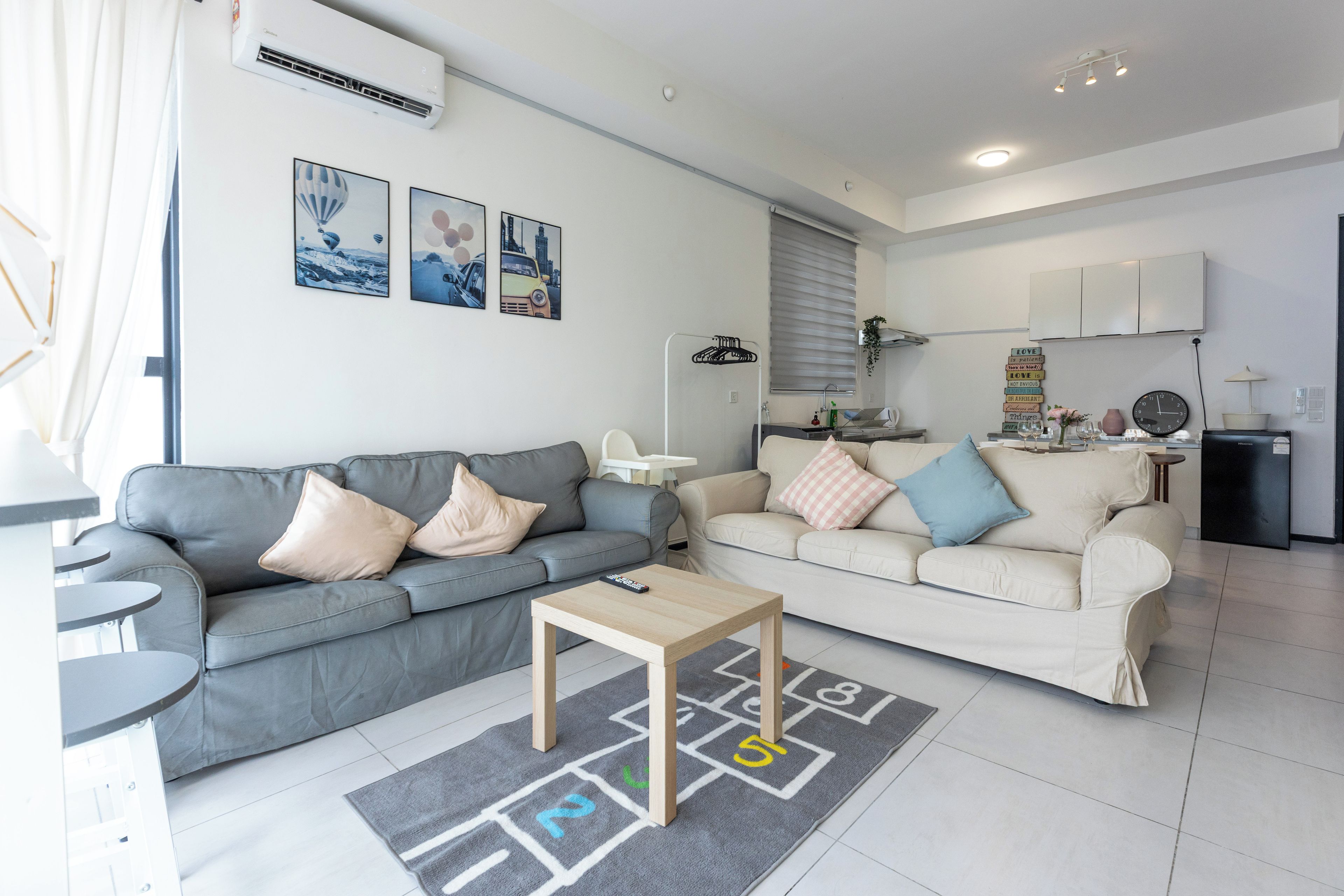 A modern living room with two sofas, a coffee table, and a play mat.