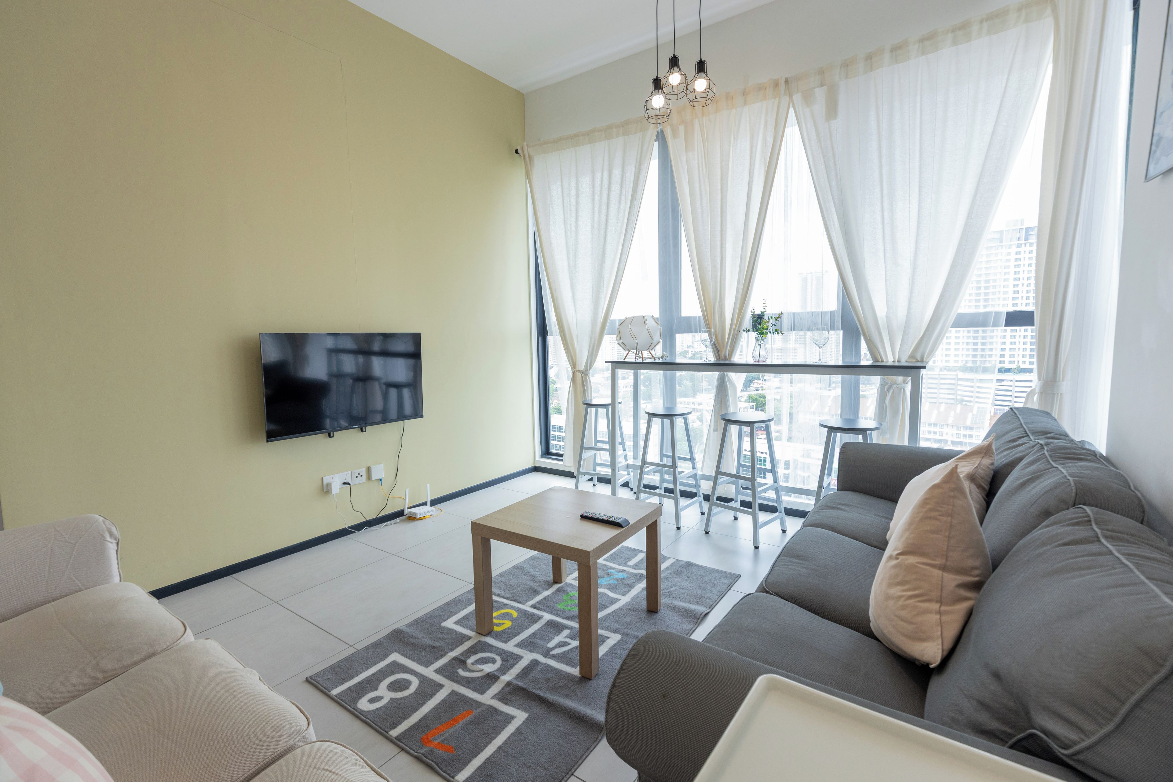 A modern living room with a flat-screen TV, a sofa, a coffee table, and a play mat.