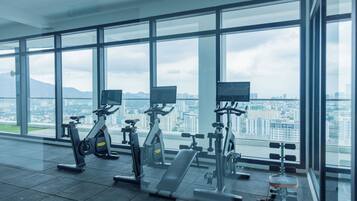A gym with exercise equipment and large windows overlooking a cityscape.