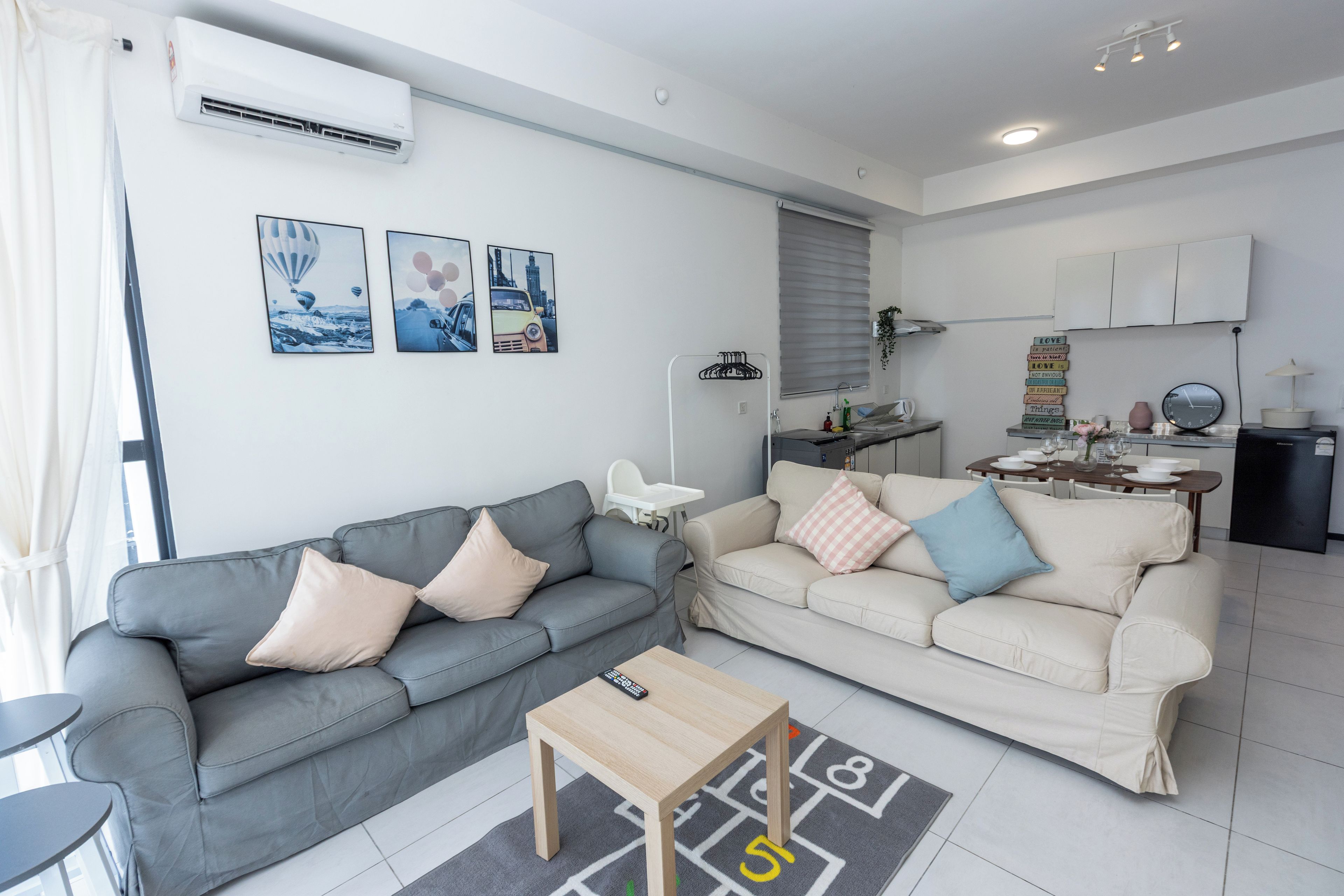 A modern living room with two sofas, a coffee table, and a kitchen area with a dining table.
