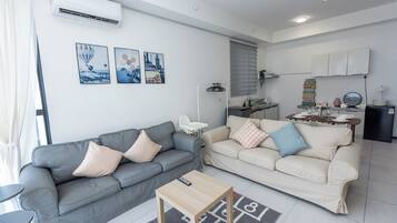 A modern living room with two sofas, a coffee table, and a kitchen area with a dining table.