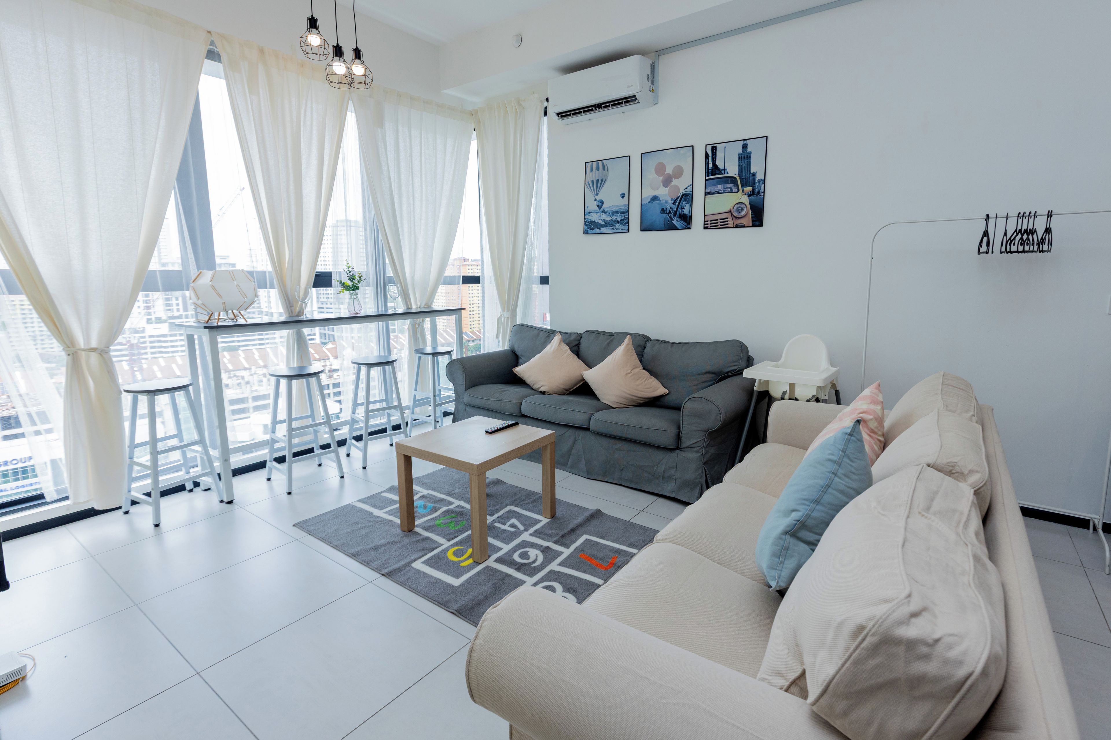 A modern living room with a grey sofa, a beige sofa, a coffee table, and a dining area with a white table and chairs.