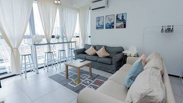 A modern living room with a grey sofa, a beige sofa, a coffee table, and a dining area with a white table and chairs.