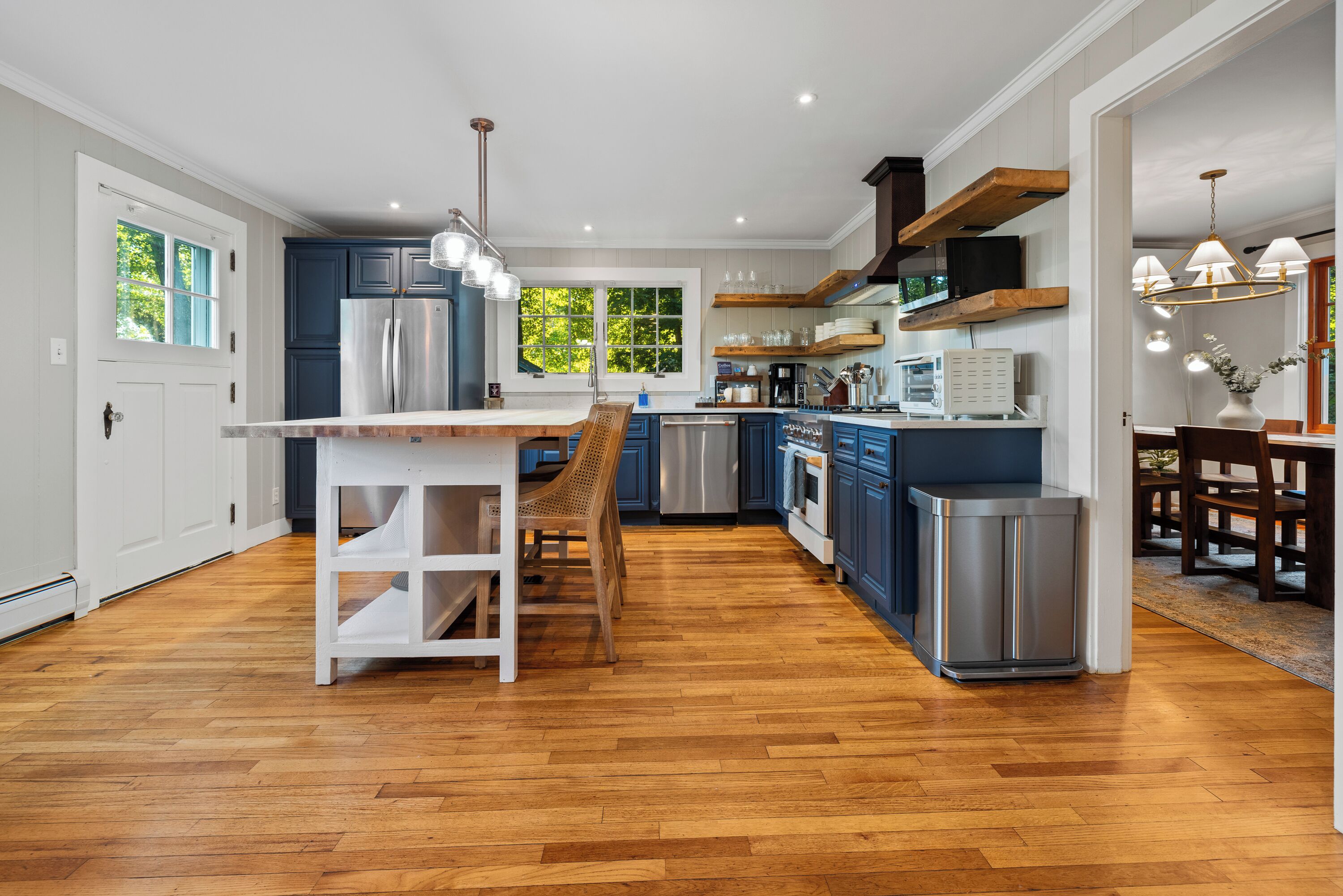 A modern kitchen with wooden flooring, stainless steel appliances, and a central island.