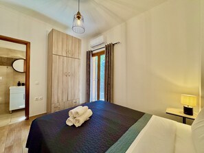 A bedroom with a bed, a bedside table with a lamp, a wardrobe, and a window with curtains.