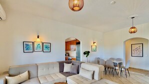 A modern living room with a sectional sofa, a coffee table, and a dining area with chairs. - Villa Anafoufou Afionas with private heatable pool (Afionas)