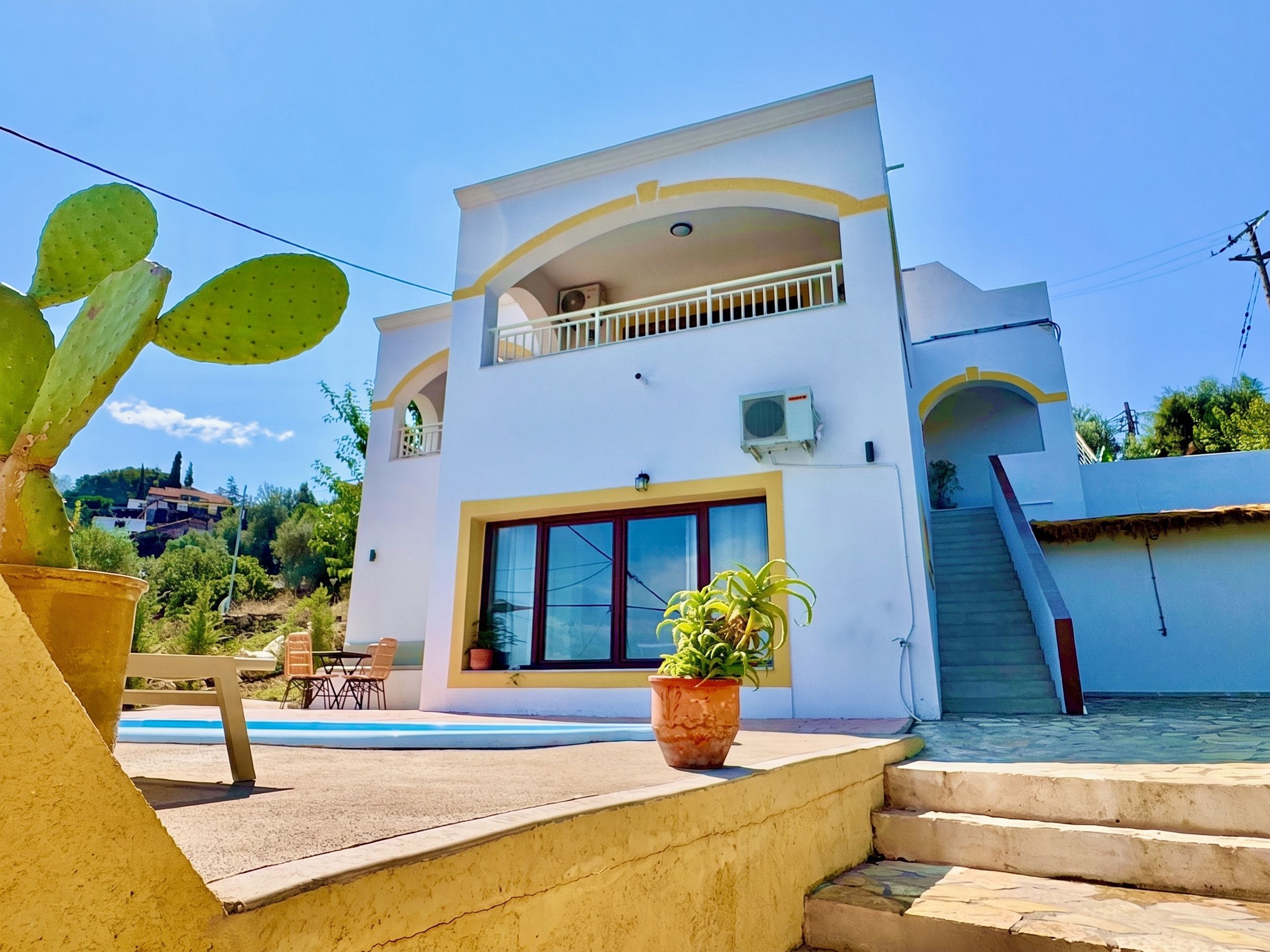 Un bâtiment à deux étages doté d’un balcon, d’une piscine et d’un escalier menant à un niveau inférieur.