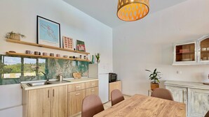 A modern kitchen with wooden cabinets, a marble backsplash, and a dining area with a wooden table and chairs. - Villa Anafoufou Afionas with private heatable pool (Afionas)