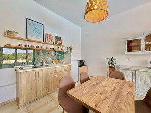 Eine moderne Küche mit Holdekor, einer Marmor-Spritzschutzwand und einem Essbereich mit Holztisch und -stühlen.