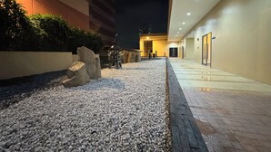A nighttime view of a hotel corridor with a pebble pathway, a lantern, and a building entrance. - 康宿·海映居 | KanStay Oceanview Residence 4005 | 2BR 2BA · Manila Bay View (Manila)