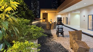 An outdoor area with a pathway, rocks, and plants. There are buildings in the background. - 康宿·海映居 | KanStay Oceanview Residence 4005 | 2BR 2BA · Manila Bay View (Manila)