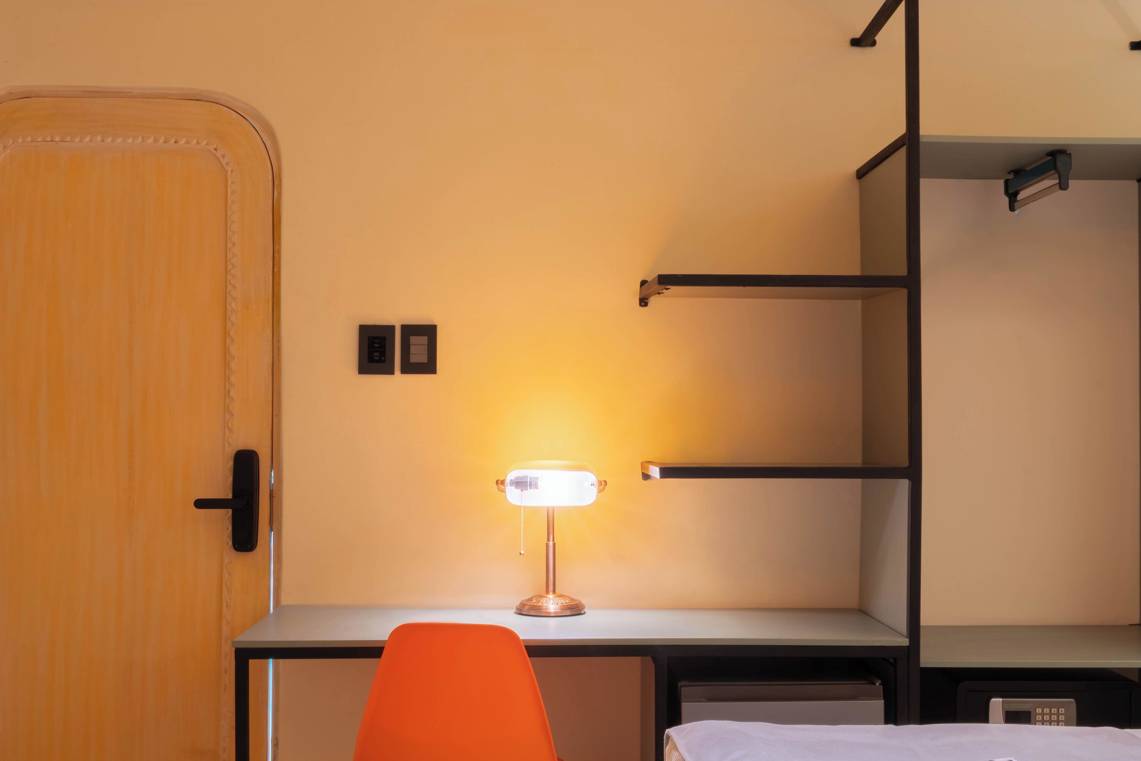 Ein gemütliches Zimmer mit Schreibtisch, Stuhl, Bett und Kleiderschrank.