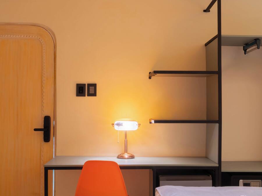 Ein gemütliches Zimmer mit Schreibtisch, Stuhl, Bett und Kleiderschrank.